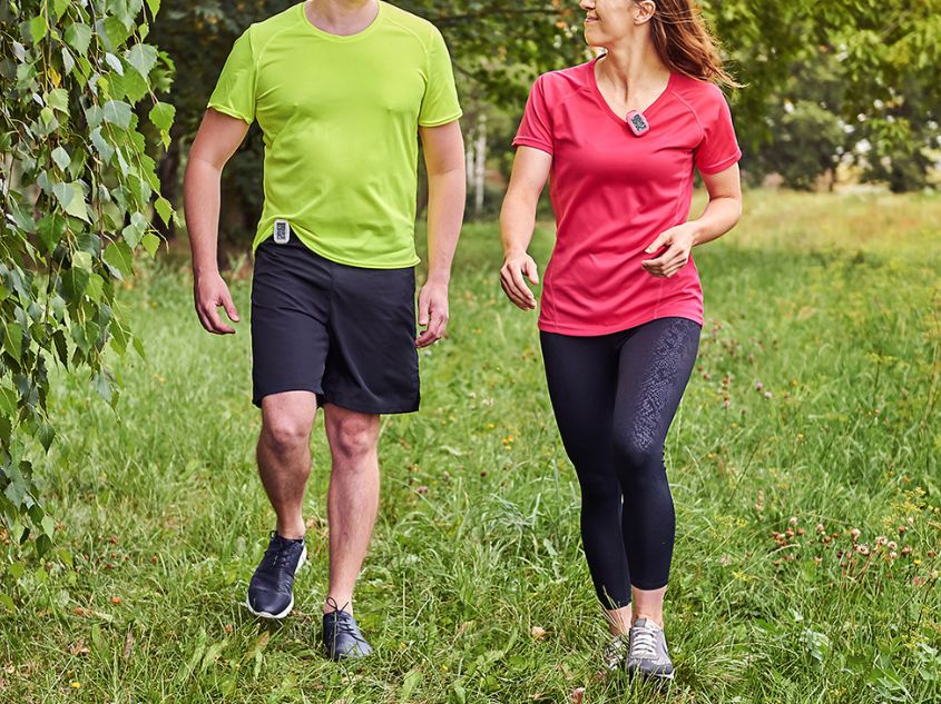 Man and woman walking on grass using their 3DFitBud Simple Step Counter