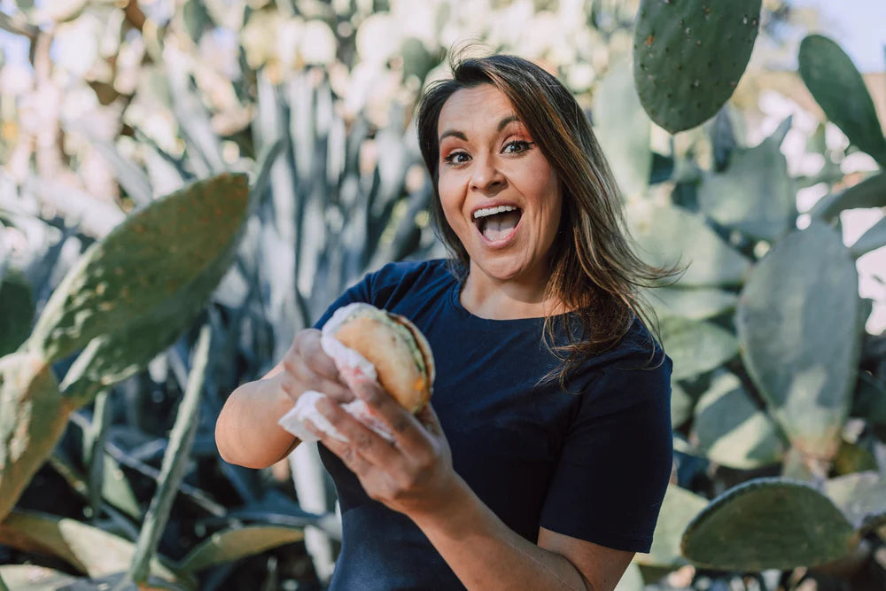 Woman happily holding a big burger about to take a bite.