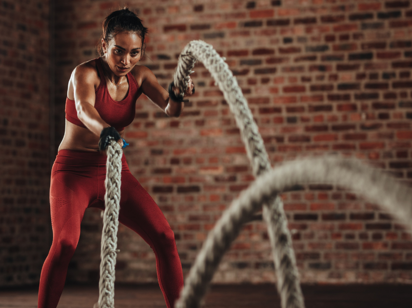 Athletic woman performing high-intensity interval training workout battle rope