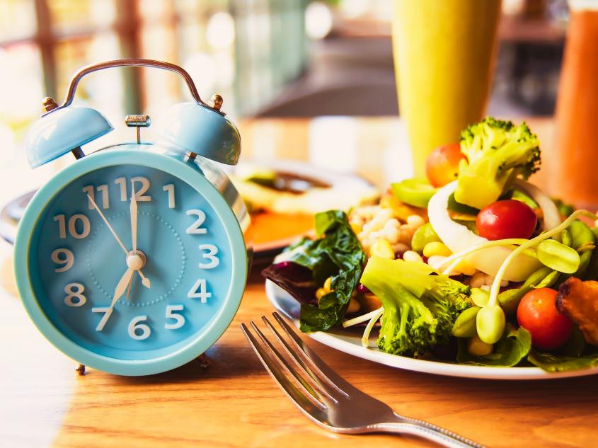 Light blue alarm clock next to plate filled with vegetables
