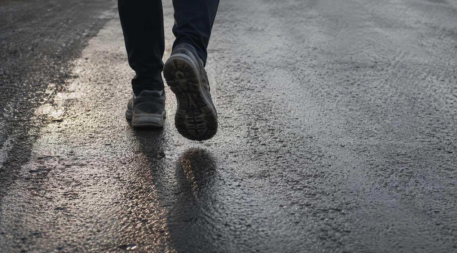 Person mid-stride on tarmac, steps in a mile